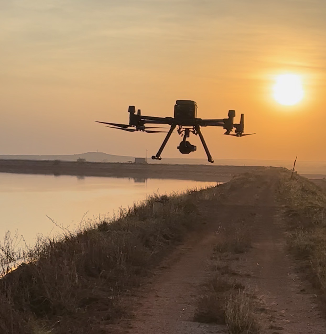 Drone surveying at sunrise over water